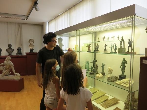 Kinder und Museumsguide betrachten eine Vitrine