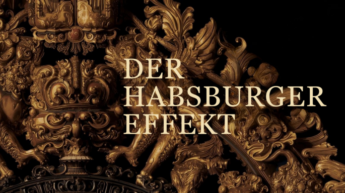 Im Zentrum des Bildes steht der Schriftzug 'DER HABSBURGER EFFEKT' in hellen, serifenbetonten Großbuchstaben. Der Text ist umgeben von opulenten, dreidimensional wirkenden, goldenen Verzierungen im Barock-Stil auf einem schwarzen Hintergrund, die an ein prunkvolles königliches Wappen erinnern.