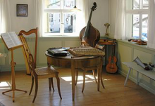 Raum eines Museums mit Harfe, Kontrabass, Gitarre, Flöte, Zither, Hackbrett und Notenständer