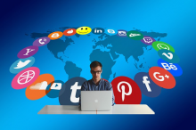 Mann an Notebook im Hintergrund Logos verschiedener Sozialen Plattformen