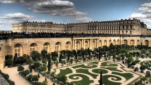 Schloss Versailles von schräg oben fotografiert mit einem kleinen Ausschnitt der Gartenanlage im Vordergrund
