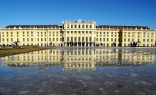 Frontansicht von Schloss Schönbrunn, davor eine Wasserfläche, auf der sich Schloss Schönbrunn spiegelt