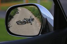 Rückspiegel eines Autos, in dem sich ein am Boden liegendes Fahrrad spiegelt