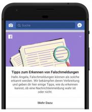 Smartphonedisplay, mit einer Zeitung und einer Lupe darauf abgebildet