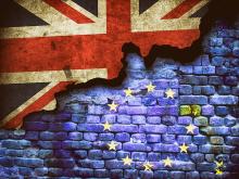blaue Ziegelmauer mit den europäischen Sternen drauf, in der linken oberen Ecke eine britische Fahne, deren Rand teilweise fehlt