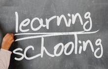 Tafel, auf der mit weißer Schrift die Wörter "learning" und "schooling" geschrieben wurden