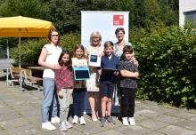 LRin Beate Palfrader übergibt der Schulleitung der VS Arzl, Direktorin Andrea Schwerma und Stellvertreterin Petra Eichler, das Gütesiegel „Digitalisierung“. Auch die Schüler*innen dürfen sich über die Auszeichnung freuen. 