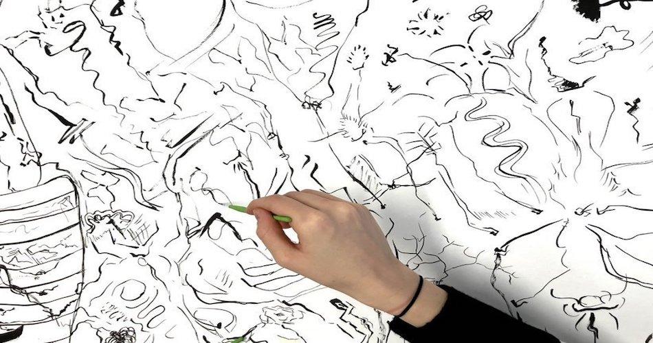 Hand malt mit Bleistift auf eine Wand